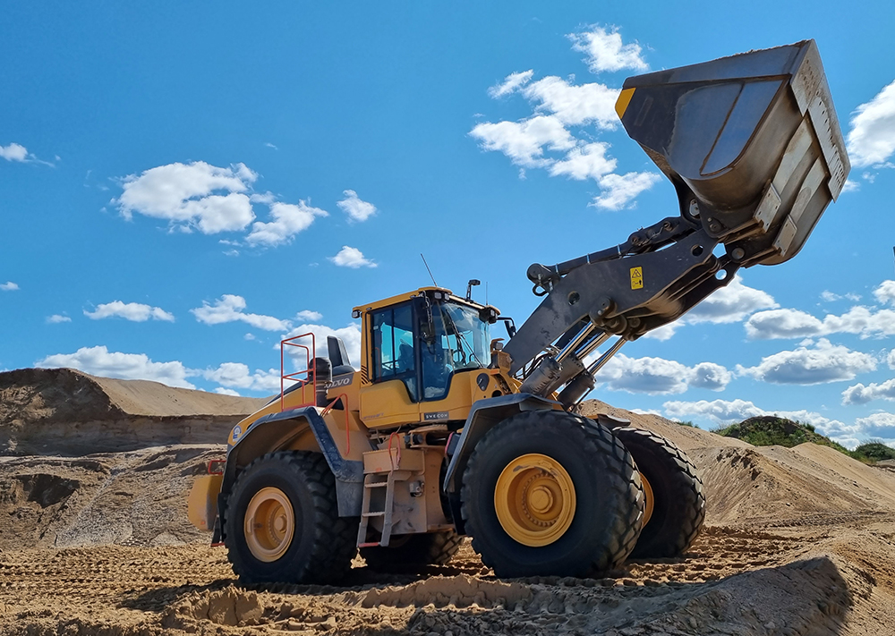 A Volvo wheeled loader loading material onto a truck at an AS Silikaat sand mine pit