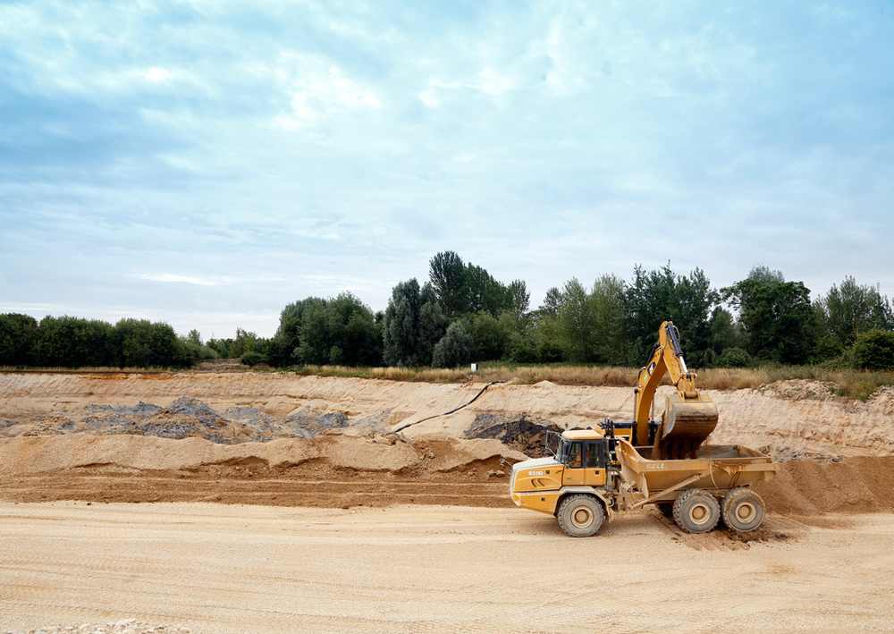 An excavator and articulated dump truck at work on a UK quarry site