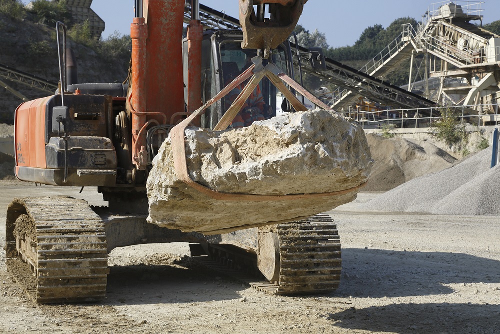 An excavator handling large rocks at a UK quarry