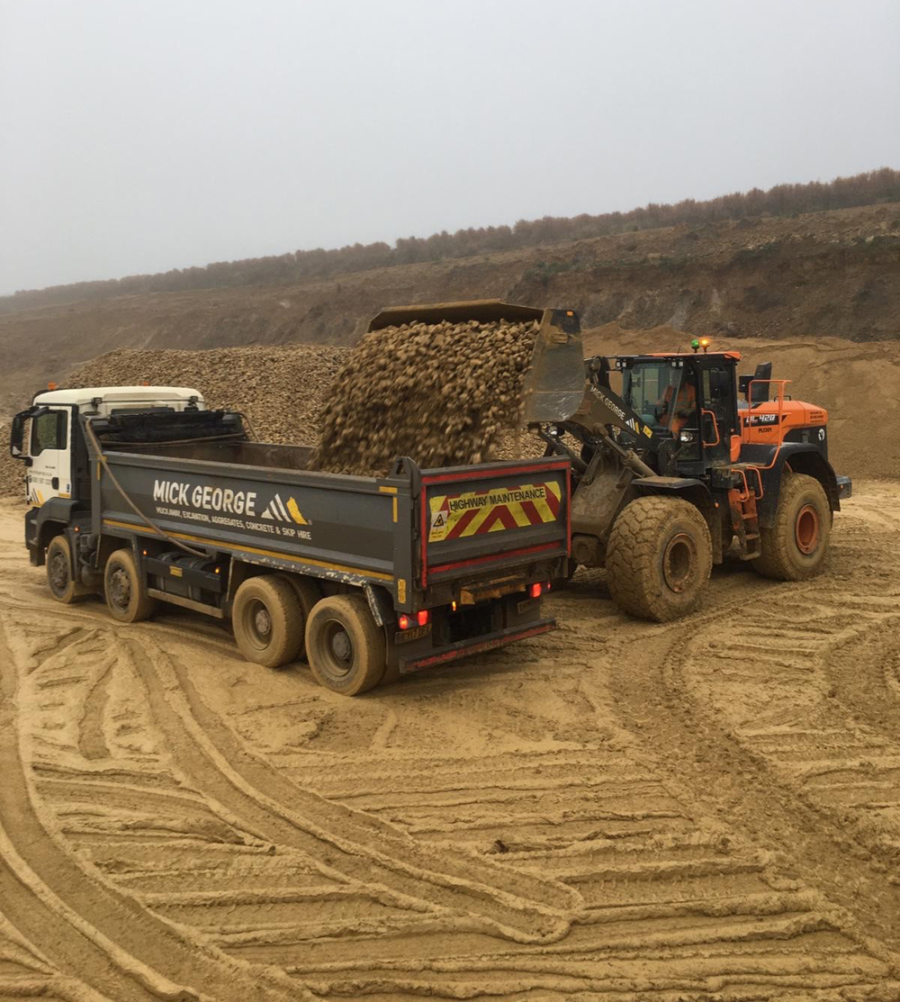 A Doosan DL-7 series loader filling up a Mick George Group truck with quarry processed material