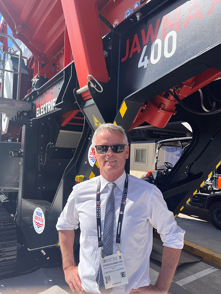  Erwin Schneller, SBM Mineral Processing managing director, in front of the JAWMAX 400 diesel-electric hybrid jaw crusher at CONEXPO/CON-AGG 2023