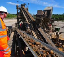 Quarry worker standing by conveyors in operation