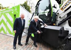  Boris Johnson refuels the prototype hydrogen-powered backhoe loader, watched by JCB chairman Lord Bamford