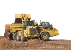 Wheeled loader filling up a dump truck with soil