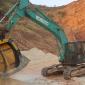 An MB Crusher MB-S18 screening bucket attached to a Kobelco SK220SD excavator screening sandstone in an Indian quarry